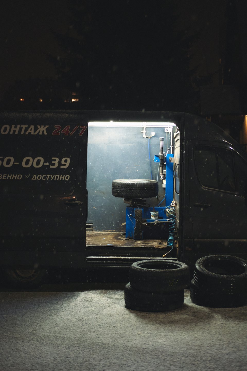 Mobile tire repair van open at night with illuminated equipment.