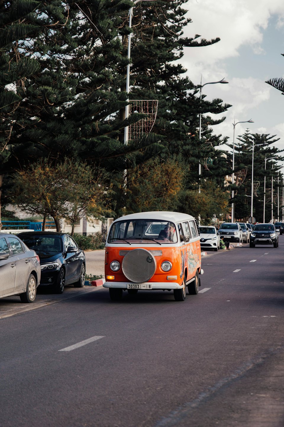 Vintage orange and white van driving down a city street.